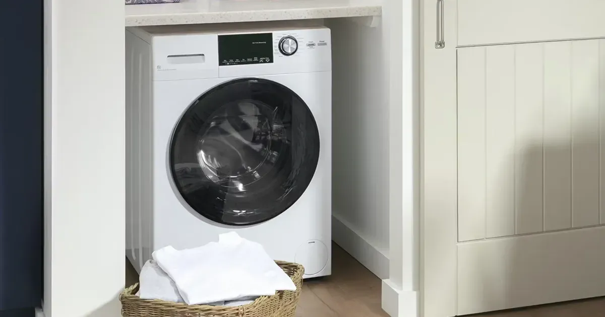 GE GFQ14ESSNWW white compact washer and ventless electric dryer combo unit under a countertop, ideal for saving space in small laundry areas.